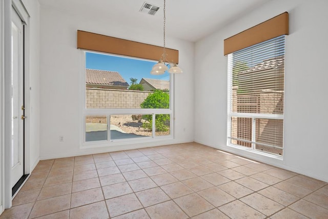 unfurnished dining area with light tile patterned floors, a wealth of natural light, and a chandelier