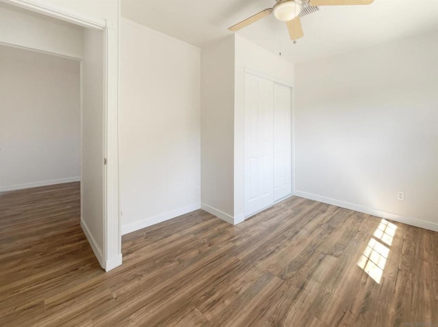 unfurnished bedroom with ceiling fan, dark hardwood / wood-style flooring, and a closet