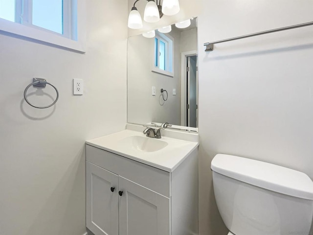 bathroom with vanity, toilet, and an inviting chandelier