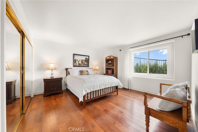 bedroom featuring baseboards, hardwood / wood-style floors, and a closet