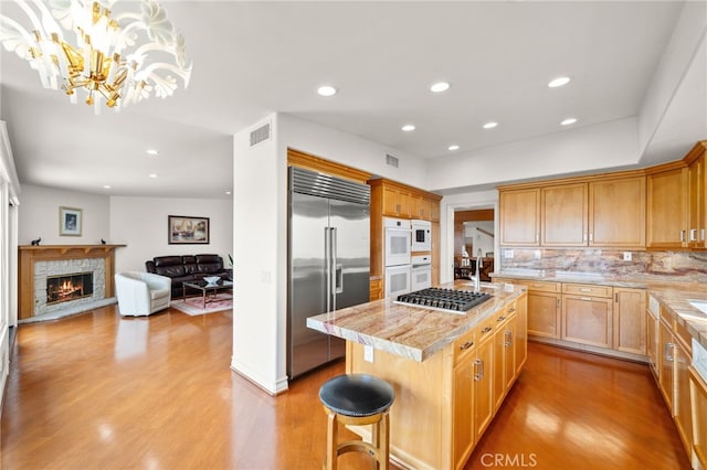 kitchen with hanging light fixtures, light hardwood / wood-style floors, a breakfast bar, stainless steel appliances, and a center island