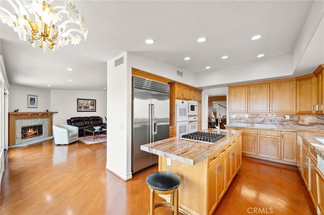 kitchen with stainless steel appliances, open floor plan, light wood-type flooring, decorative backsplash, and a kitchen island