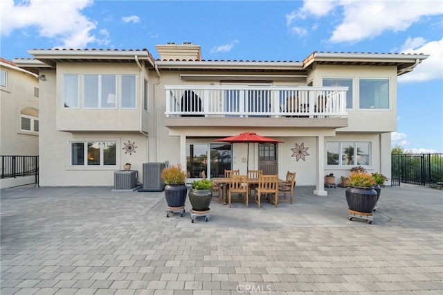 rear view of house featuring a patio, stucco siding, central AC, and a balcony