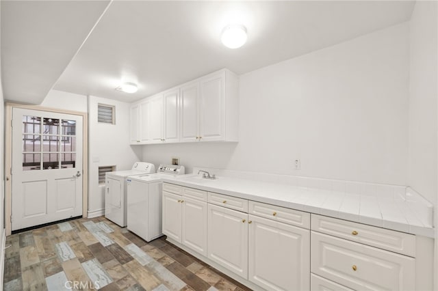 laundry room with light wood-type flooring, washer and clothes dryer, and cabinets