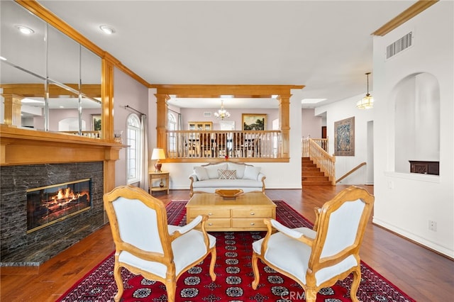 living room featuring decorative columns, ornamental molding, a chandelier, and hardwood / wood-style flooring