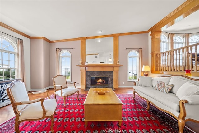 living area featuring a premium fireplace, ornamental molding, baseboards, and wood finished floors