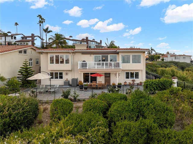 back of property with a balcony, a patio, and central AC