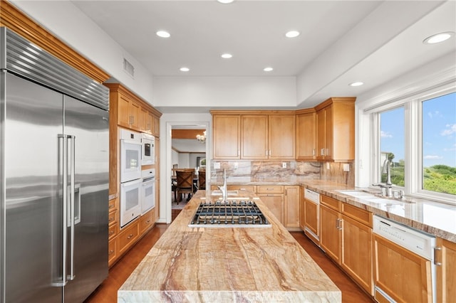 kitchen featuring dark hardwood / wood-style floors, sink, built in appliances, and tasteful backsplash