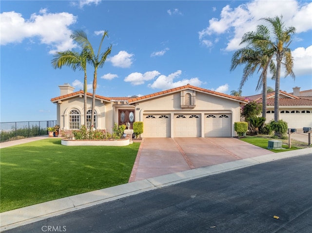 mediterranean / spanish-style home featuring a chimney, driveway, an attached garage, stucco siding, and a front lawn