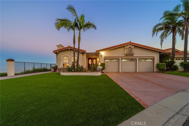 mediterranean / spanish house with a yard, driveway, a chimney, an attached garage, and stucco siding