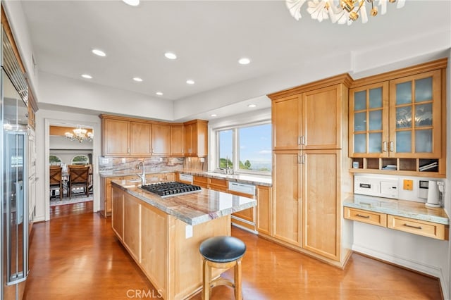 kitchen featuring an island with sink, light wood-style floors, an inviting chandelier, and appliances with stainless steel finishes
