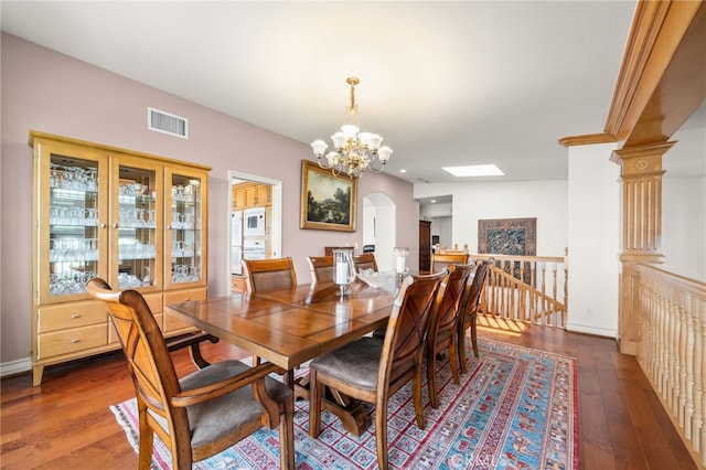 dining space featuring visible vents, hardwood / wood-style flooring, arched walkways, and a notable chandelier