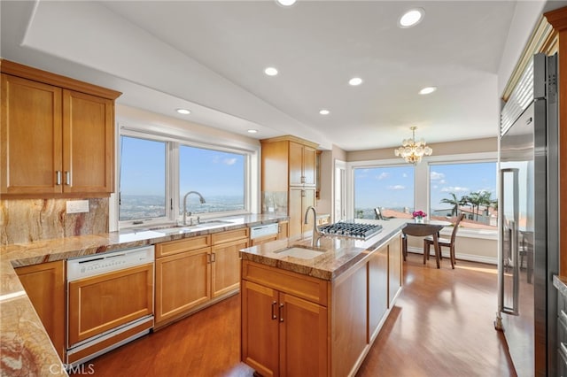 kitchen featuring wood-type flooring, sink, hanging light fixtures, decorative backsplash, and stainless steel appliances