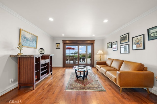 living room featuring baseboards, recessed lighting, ornamental molding, and light wood-type flooring