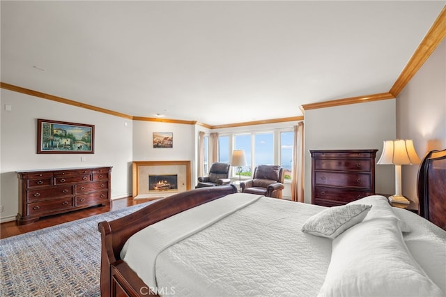 bedroom featuring baseboards, ornamental molding, a lit fireplace, and dark wood-style floors