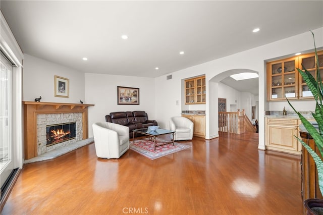 living room with arched walkways, a fireplace, recessed lighting, and wood finished floors