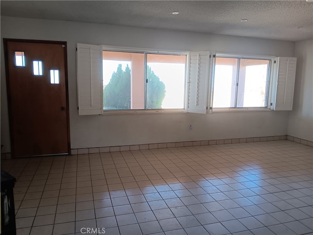 interior space with light tile patterned floors, a wealth of natural light, and a textured ceiling