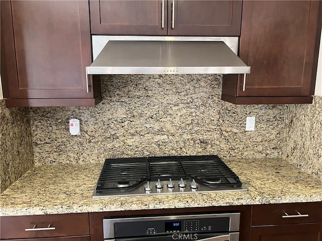 kitchen featuring wall chimney exhaust hood, stainless steel appliances, light stone counters, and decorative backsplash