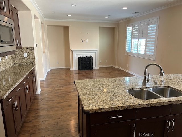 kitchen with dark hardwood / wood-style flooring, crown molding, light stone countertops, and sink