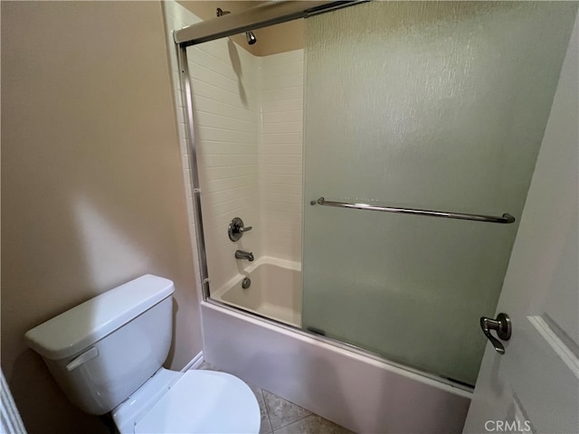 bathroom with tile patterned flooring, shower / bath combination with glass door, and toilet