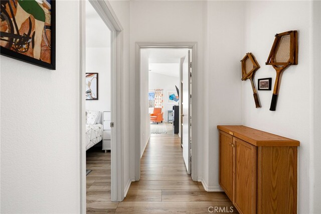 hallway featuring lofted ceiling and light wood-type flooring