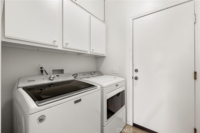 laundry area featuring washing machine and dryer, cabinets, and light wood-type flooring