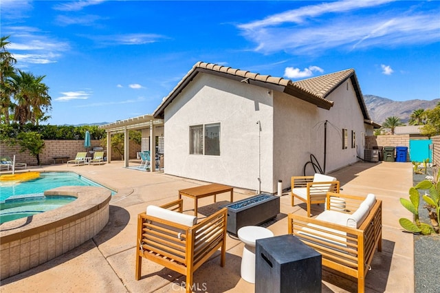 back of property with a mountain view, an outdoor hangout area, a pergola, a swimming pool with hot tub, and a patio