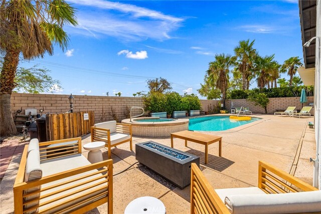 view of swimming pool with an in ground hot tub, an outdoor living space with a fire pit, and a patio