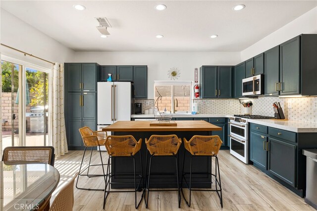 kitchen with wooden counters, a kitchen island, light hardwood / wood-style floors, and high end appliances