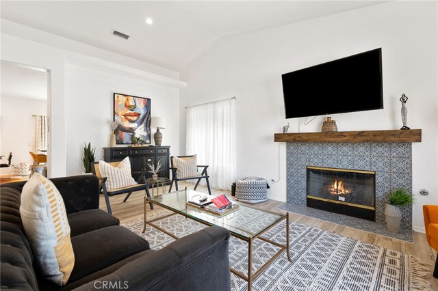 living room featuring a fireplace, wood-type flooring, and lofted ceiling