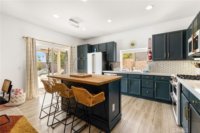 kitchen with sink, a kitchen breakfast bar, light hardwood / wood-style floors, high quality appliances, and a kitchen island