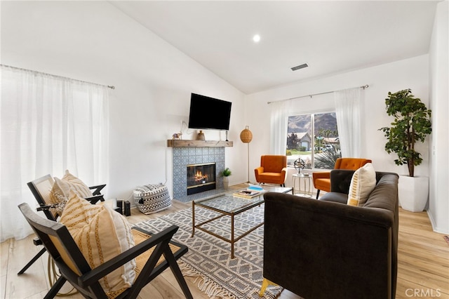 living room featuring a fireplace, light hardwood / wood-style floors, and lofted ceiling