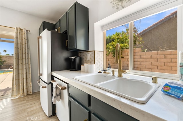 kitchen featuring tasteful backsplash, dishwasher, light hardwood / wood-style floors, and sink