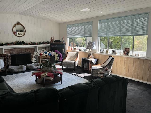 living room with wood ceiling, wood walls, a fireplace, and a wealth of natural light