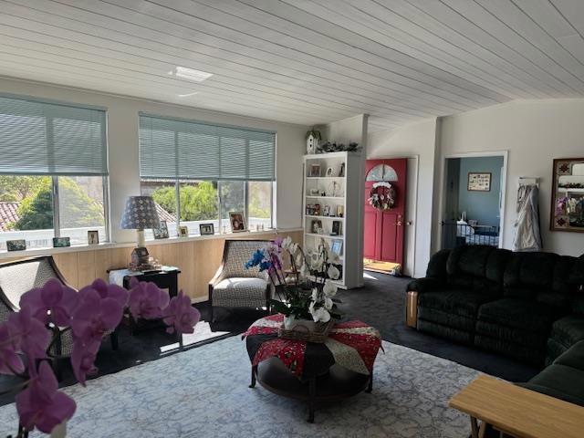 living room featuring plenty of natural light, carpet floors, and wooden ceiling