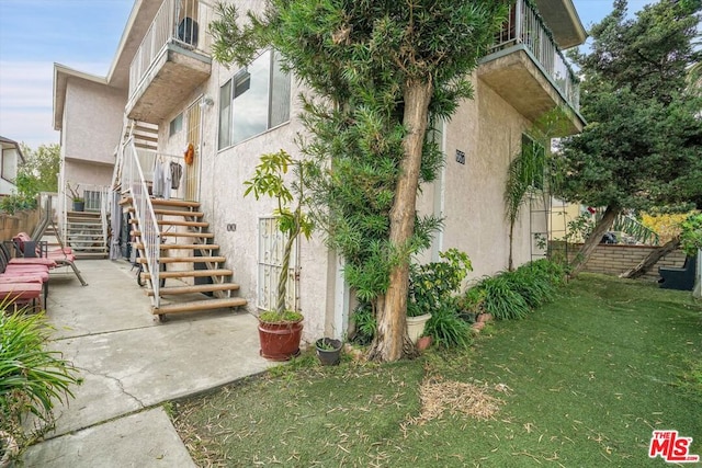 view of property exterior with a patio area and a lawn