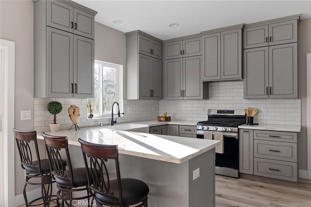 kitchen featuring kitchen peninsula, a kitchen bar, sink, and stainless steel range oven