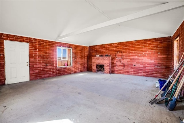 unfurnished living room with concrete flooring, vaulted ceiling with beams, a fireplace, and brick wall