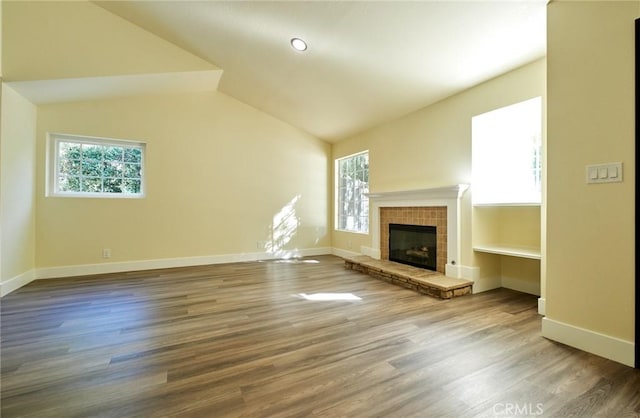 unfurnished living room featuring wood-type flooring, vaulted ceiling, and a stone fireplace