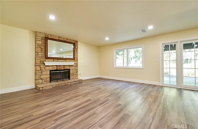 unfurnished living room featuring a stone fireplace and light hardwood / wood-style flooring