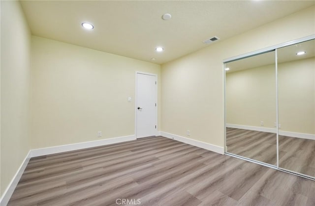 unfurnished bedroom with light hardwood / wood-style flooring and a closet