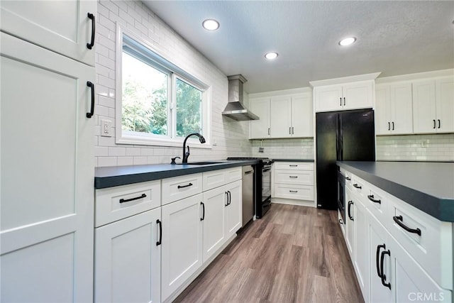 kitchen featuring tasteful backsplash, wall chimney exhaust hood, sink, hardwood / wood-style flooring, and white cabinets