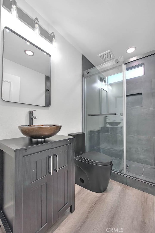 bathroom featuring vanity, hardwood / wood-style flooring, toilet, and walk in shower