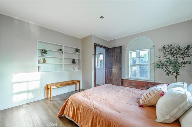 bedroom with ornamental molding and light hardwood / wood-style flooring