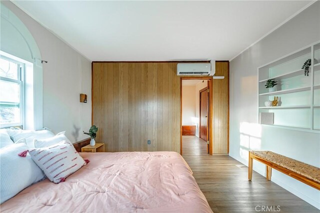 bedroom with wood-type flooring, crown molding, a wall mounted AC, and wooden walls