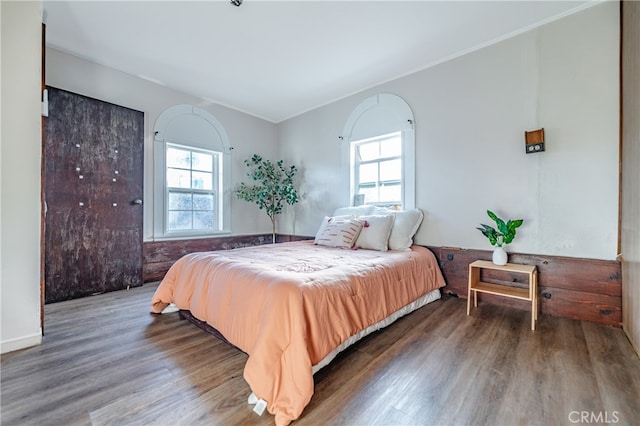 bedroom with dark hardwood / wood-style floors, ornamental molding, and multiple windows