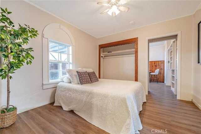 bedroom with hardwood / wood-style floors, crown molding, a closet, and ceiling fan