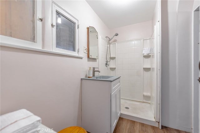 bathroom with walk in shower, vanity, and hardwood / wood-style floors