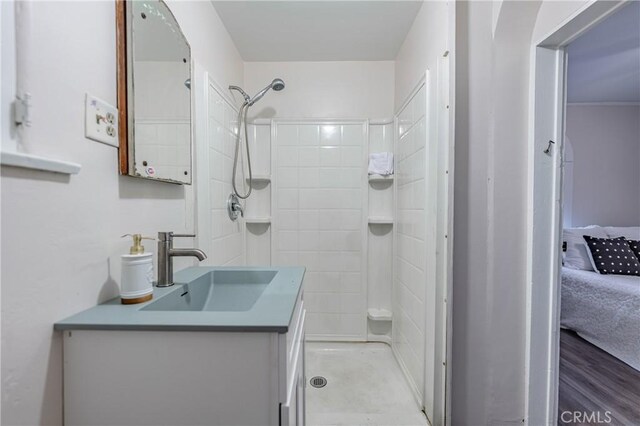 bathroom with hardwood / wood-style floors, tiled shower, and vanity