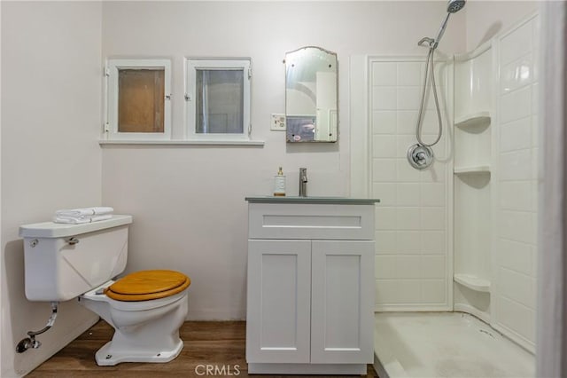 bathroom with hardwood / wood-style flooring, vanity, toilet, and a shower